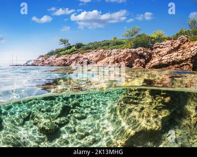 Split view - vista a metà sottomarina di splendidi fondali marini e costa rocciosa con pini, tacchino, Bodrum. Foto Stock