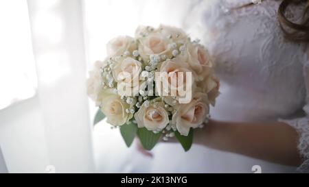 Sposa in abito da sposa che tiene bello bianco bouquet di fiori da sposa. Foto Stock