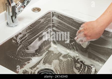 Lavello in acciaio in cucina nella schiuma del detergente Foto Stock
