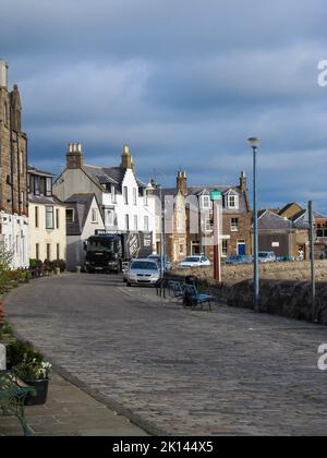 Strada acciottolata al mattino, presso il porto del piccolo villaggio di pescatori scozzese di Stonehaven, con minacciose nuvole blu d'acciaio sullo sfondo Foto Stock