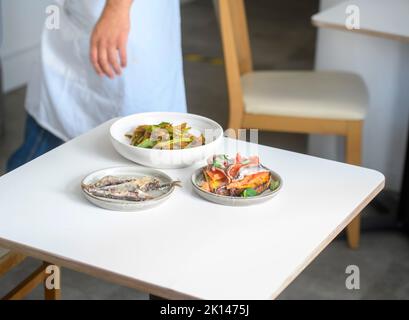 Tre piatti presentati in una semplice sala da pranzo. Foto Stock