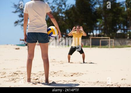 Giovane coppia che gioca a pallavolo sulla spiaggia di sabbia Foto Stock