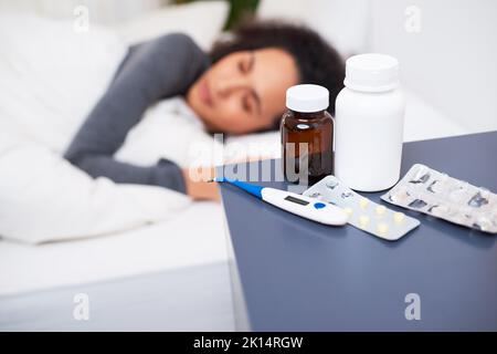 Focalizzazione selettiva sul comodino di una donna malata con flaconi per pillole e termometro Foto Stock