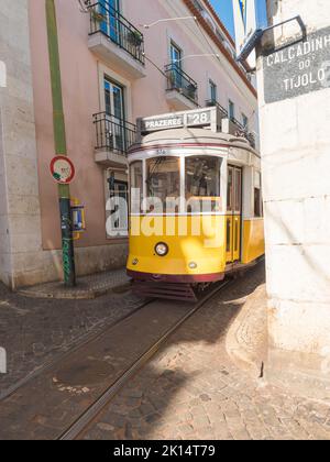 Lisbona, Portogallo, 24 ottobre 2021: Vista ravvicinata della tipica linea gialla del tram vintage numero 28 che scende lungo la stretta e ripida strada di Lisbona con, icona e. Foto Stock