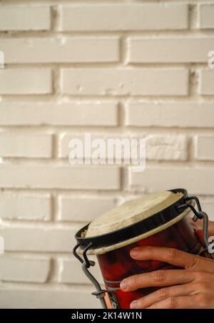 tamburo africano con sfondo di mattoni bianchi. Verticale Foto Stock