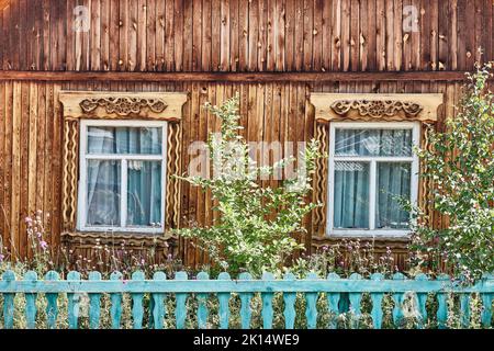 Vecchie finestre in legno con architravi scolpiti sulla facciata in legno della casa a Buryatia, Russia Foto Stock