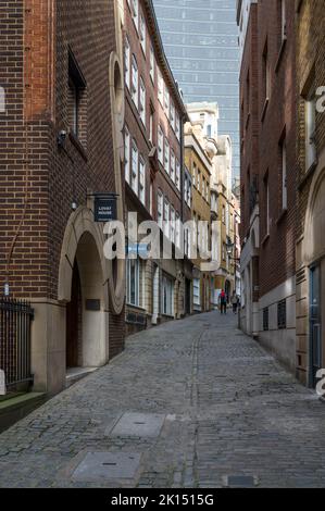 Giovane uomo e donna camminano in salita lungo Lovat Lane, una stretta strada acciottolata nella City of London, England, UK Foto Stock