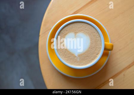Tazza di cappuccino appena servita con latte art su un tavolo di legno in un bar. Foto Stock