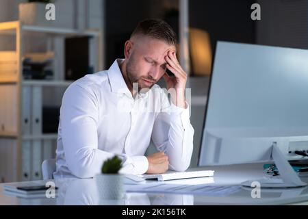 Stressante uomo d'affari che lavora in ritardo sul laptop in ufficio Foto Stock