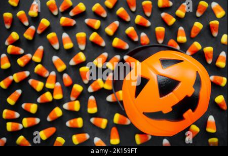 Halloween sfondo caramelle di mais caramelle, cestino di zucca. Dolci tradizionali. Spazio di copia. Foto Stock