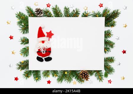 Layout per Natale, Capodanno con spazio per le copie. Babbo Natale in cornice di rami di abete naturale, pineconi e decorazioni su fondo piatto bianco Foto Stock