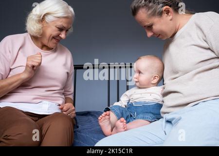 Madre, bambina e nonna seduti sul divano a casa Foto Stock