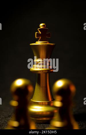 Gli scacchi d'oro sono pezzi di re e di regina su uno sfondo nero. Foto Stock