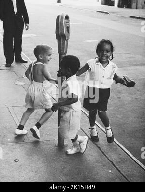 Tre bambini oscillano intorno ad un parchimetro nel Greenwich Village di New York. Circa anni '60. Foto Stock