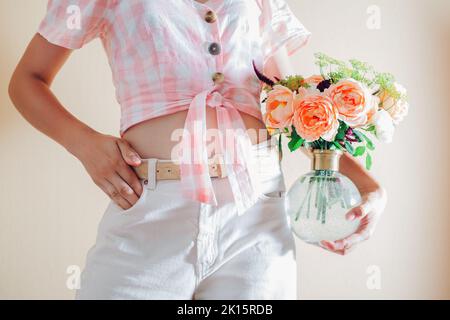 Primo piano di vaso con bouquet di fiori freschi in mani femminili. Fresco allestimento floreale con rose bianche arancioni e verde. Fiori estivi Foto Stock