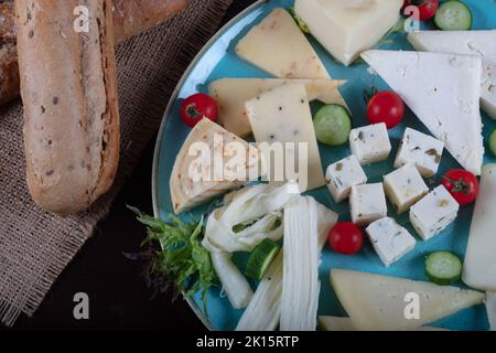 Piatto di formaggi su un tavolo scuro. Molti tipi di formaggio su un piatto Foto Stock