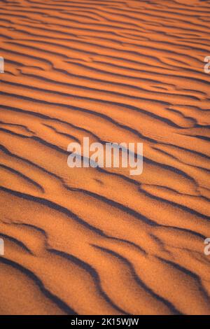 Sfondo a cornice pieno di superficie di sabbia ondulata su spiaggia arida al tramonto in natura Foto Stock