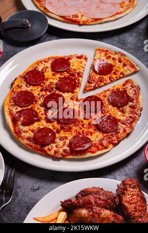 Vista dall'alto del piatto con deliziosa pizza peperoni e ciotola di salsa posta sul tavolo grigio durante il pranzo Foto Stock