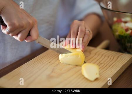 Una donna per affettare formaggio morbido su una scheda di formaggio, con  vari ortaggi Foto stock - Alamy