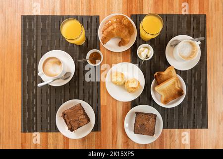 Vista dall'alto di vari tipi di pasticcini e bevande, posti vicino a bocce con salse sul tavolo durante la colazione nel ristorante Foto Stock