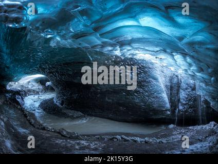 Grotta di ghiaccio Skaftadell con pareti blu ruvide e ruscello nella fredda giornata invernale in Islanda Foto Stock