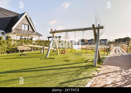 Moderno parco giochi all'aperto con scivoli situato nel quartiere residenziale della città con edifici contemporanei contro il cielo blu nuvoloso Foto Stock