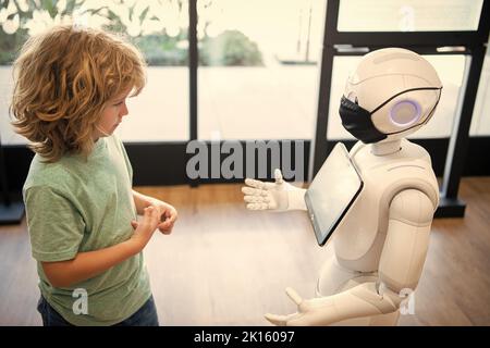 il bambino concentrato interagisce con l'intelligenza artificiale del robot, la comunicazione Foto Stock