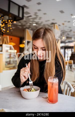 giovane ragazza che mangia in un bar Foto Stock