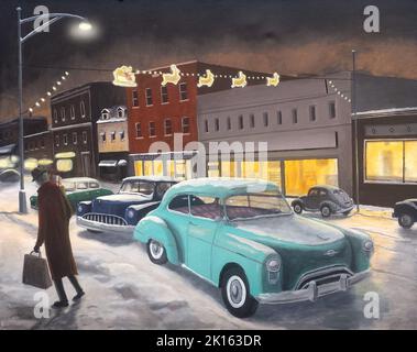 Retro 1950s scena di un uomo che fa shopping tardi la vigilia di Natale in una piccola città nordamericana. Foto Stock