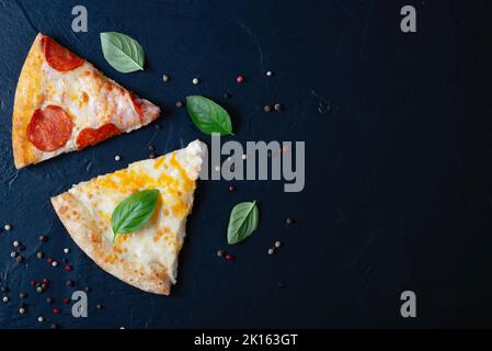 Due deliziose fette di pizza, basilico e pepe Foto Stock