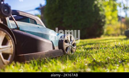 Mover prato su erba verde in giardino moderno o cortile. Macchina per il taglio di prati. Attrezzi e attrezzatura per la cura del giardinaggio Foto Stock