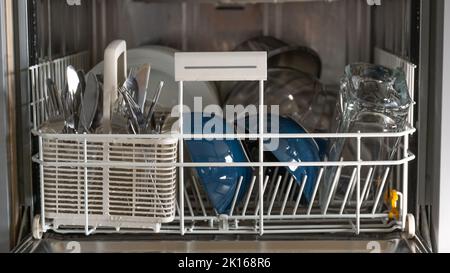 Lavastoviglie con stoviglie.elettrodomestici per la cucina. Piatti, forchette e bicchieri in lavastoviglie. Foto Stock