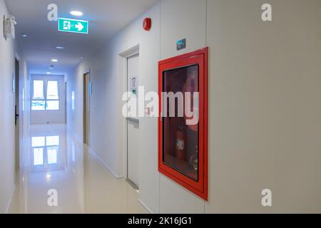 Sistema di estintore a parete con segnale di emergenza per la porta di uscita antincendio. Scalinata fuoco per fuga in edificio o appartamento Foto Stock