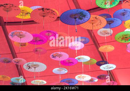 Colorati ombrelli di olio-carta appesi nell'aria Foto Stock