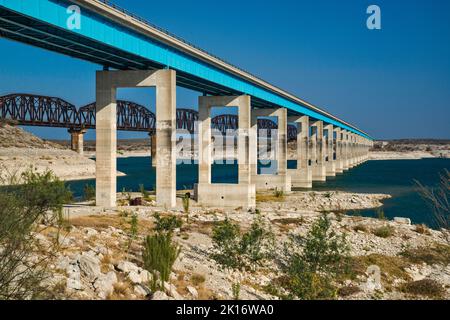 L'autostrada US-90 e i ponti ferroviari attraverso Amistad Reservoir, livello dell'acqua molto basso in aprile 2022, segni di alto livello visibile sui moli, vicino al del Rio, TX Foto Stock