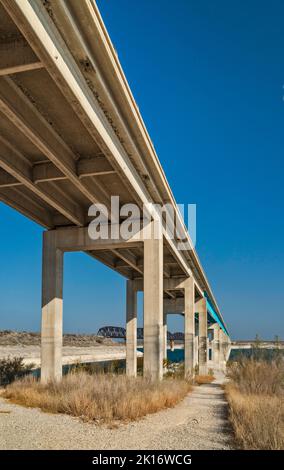 L'autostrada US-90 e i ponti ferroviari attraverso Amistad Reservoir, livello dell'acqua molto basso in aprile 2022, segni di alto livello visibile sui moli, vicino al del Rio, TX Foto Stock