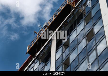 Piattaforma sospesa senza operai su una facciata in vetro e acciaio del grattacielo Foto Stock