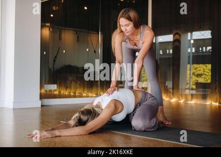 Esercizi di yoga. Un personal trainer insegna lezioni di yoga in palestra Foto Stock