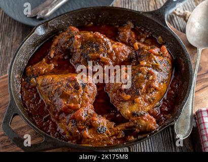 Cosce di pollo brasate con salsa di pomodoro italiana in una padella di ghisa Foto Stock