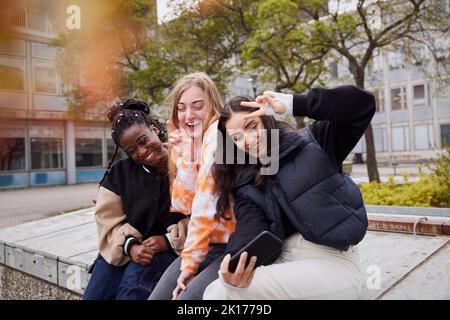 Tre giovani studentesse che prendono selfie al campus Foto Stock