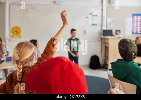 Ragazza con mano sollevata in classe Foto Stock