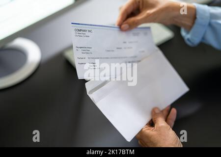 Assegno di retribuzione nella busta. Donna mano che tiene il controllo di paga Foto Stock