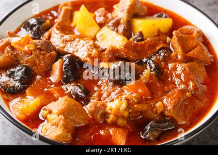 Stufato di agnello piccante con prugne, pomodori, patate e zafferano primo piano su un piatto sul tavolo. Cibo iraniano. Orizzontale Foto Stock