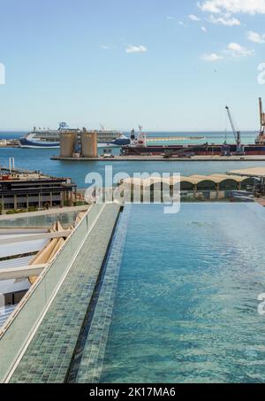 Piccola piscina a sfioro sul tetto dell'hotel, con il porto di Malaga sullo sfondo, Costa del Sol, Andalusia, Spagna. Foto Stock