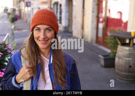 Donna caucasica che indossa una beanie e tiene uno zaino all'aperto Foto Stock