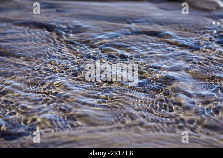 Bella pura acqua pulita oceano increspature superficie senza cuciture modello astratto texture design natura sfondo immagine concetto. sole riflessione sull'acqua. Foto Stock