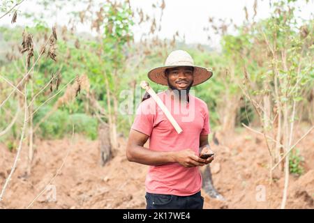 agricoltore africano che utilizza il suo telefono per inviare messaggi o sms Foto Stock