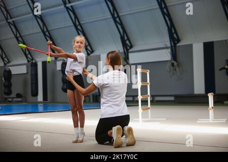 Bambine, atleti di ginnastica principianti che fanno esercizi con attrezzature di ginnastica in palestra sportiva, al coperto. Concetto di studio, realizzazioni, abilità Foto Stock