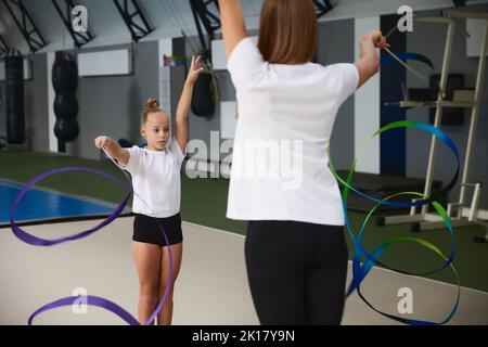 Coaching. Atleti di ginnastica principianti che fanno esercizi con attrezzature di ginnastica in palestra sportiva, al coperto. Concetto di sport, studio, arte, educazione Foto Stock