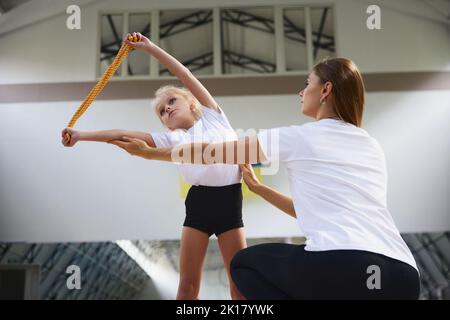 Coaching. Atleti di ginnastica principianti che fanno esercizi con attrezzature di ginnastica in palestra sportiva, al coperto. Concetto di sport, studio, arte, educazione Foto Stock